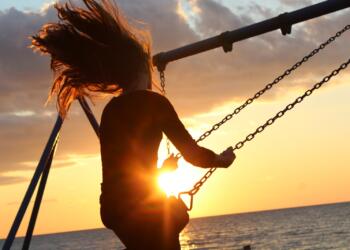 woman riding on swing during sunset
