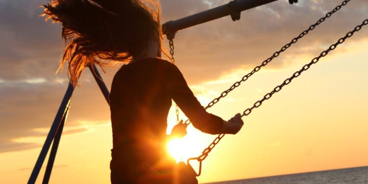 woman riding on swing during sunset