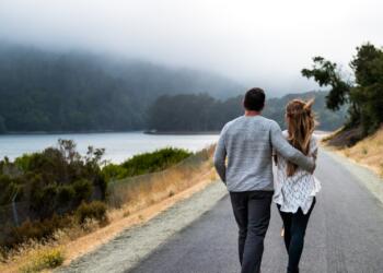 man and woman walking on asphalt road