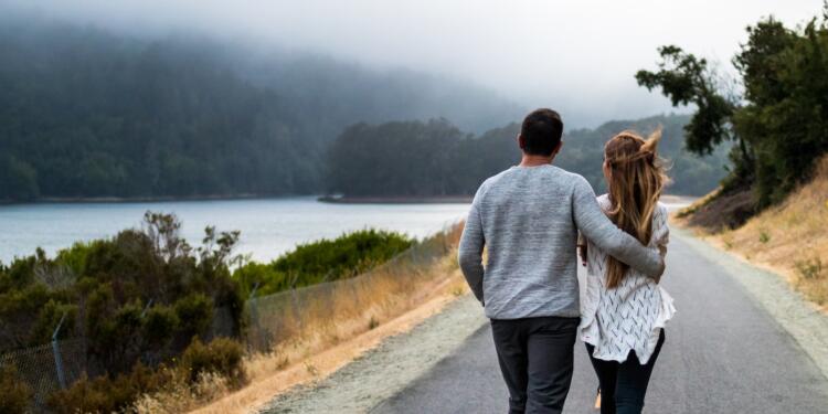 man and woman walking on asphalt road