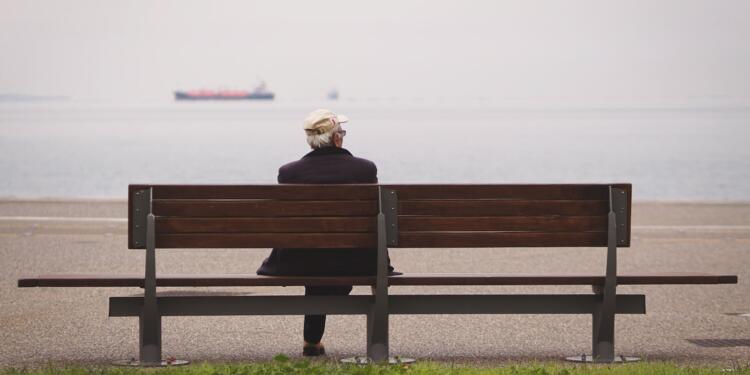 man sitting on brown bench facing on the sea