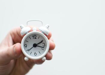 person holding white mini bell alarmclock