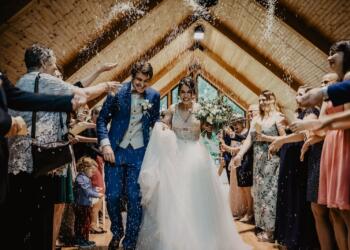 bride and groom standing beside brown wooden wall