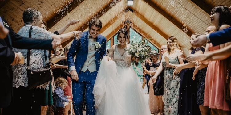 bride and groom standing beside brown wooden wall