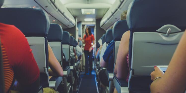 flight attendant standing between passenger seat