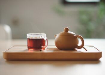 clear glass cup with tea near brown ceramic teapot