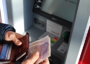 person holding brown leather wallet and banknotes