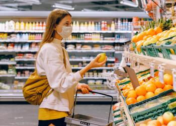 Woman in Yellow Tshirt and Beige jacket Holding a Fruit Stand