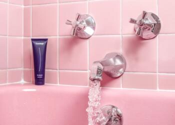 a pink bathtub with a faucet and soap dispenser