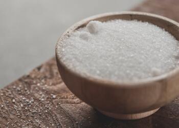 a wooden bowl filled with sugar on top of a wooden table