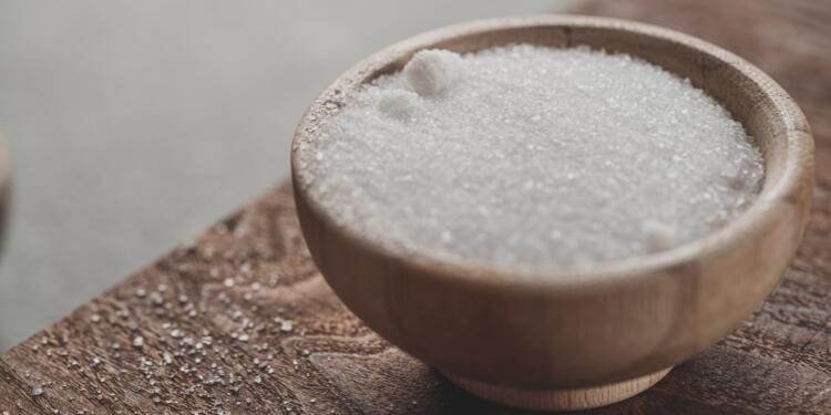 a wooden bowl filled with sugar on top of a wooden table