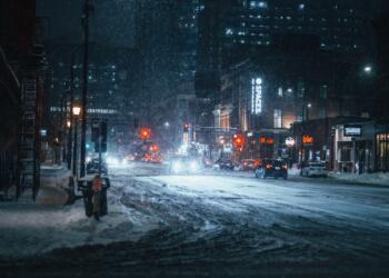 person in black jacket standing on road during snow