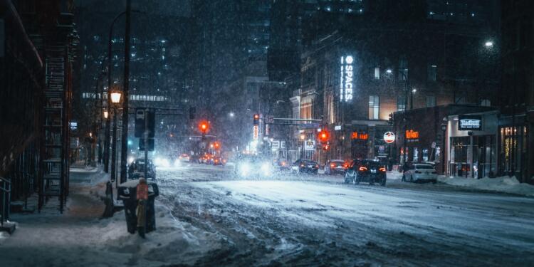person in black jacket standing on road during snow