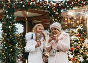 Women enjoying a festive Christmas market in Moscow, embracing winter vibes with warm drinks.