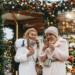 Women enjoying a festive Christmas market in Moscow, embracing winter vibes with warm drinks.