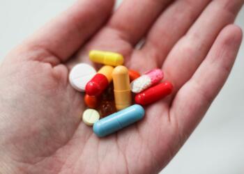 orange and white medication pill on persons hand